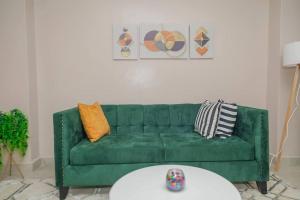 un sofá verde en una sala de estar con mesa en Lovely 1-bedroom apartment with free parking, en Nairobi