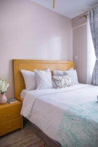 1 dormitorio con 1 cama con sábanas y almohadas blancas en Lovely 1-bedroom apartment with free parking, en Nairobi