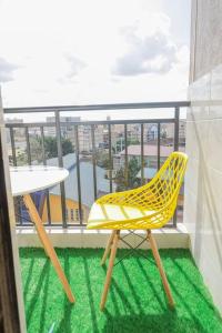 una silla amarilla y una mesa en el balcón en Lovely 1-bedroom apartment with free parking, en Nairobi