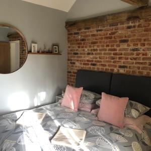 1 dormitorio con 1 cama con almohadas rosas y pared de ladrillo en Rivers Rest, en Norwich