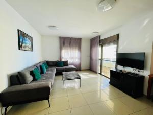 een woonkamer met een bank en een flatscreen-tv bij King David Apartment in Netanya