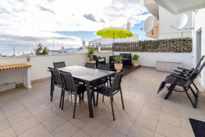 un patio con mesa, sillas y sombrilla en Casa beira mar Algarve, en Albufeira