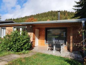 ein Haus mit einer Terrasse mit zwei Stühlen darauf in der Unterkunft Ferienhäuser & Bungalows - Naturcamp Meyersgrund im Thüringer Wald in Ilmenau