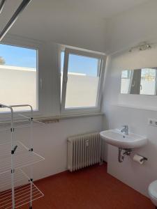 ein Badezimmer mit einem Waschbecken und zwei Fenstern in der Unterkunft Pension Messe in Feldkirchen