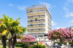 a tall building with pink flowers in front of it at Hotel Italy in Bibione