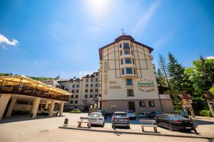 un gran edificio con coches estacionados frente a él en Romantik Spa Hotel, en Yaremche