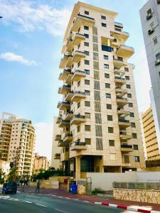 een hoog gebouw met balkons aan de straatkant bij King David Apartment in Netanya