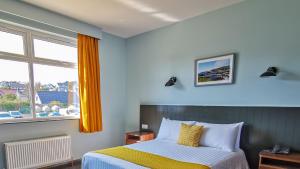 a bedroom with a bed and a window at Marine Hotel Ballycastle in Ballycastle
