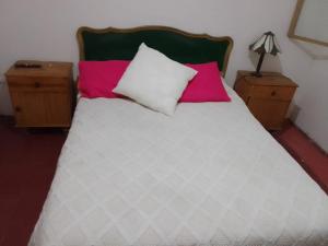 Una cama con dos almohadas rosas y blancas. en Graciela Chacras Pueyrredón en Luján de Cuyo