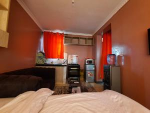 Kikuyu的住宿－Pine Residency w Secure Parking, Wifi, Netflix & Rooftop Views，一间设有床铺的客房和一间带红色窗帘的厨房