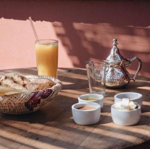 a table with a basket of bread and a glass of orange juice at Riad Musa in Marrakesh