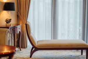una silla en una habitación de hotel con ventana en L`Art Hotel Carei en Carei