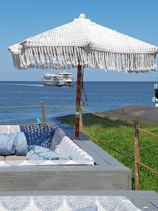 ein Bett mit einem Sonnenschirm am Meer in der Unterkunft Romantisch Huisje nabij het strand in Julianadorp