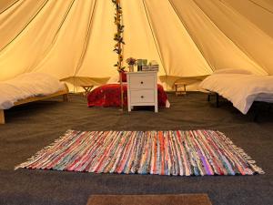 a tent with two beds and a rug on the floor at Strawberry Fields Glamping at Cottrell Family Farm in Wokingham