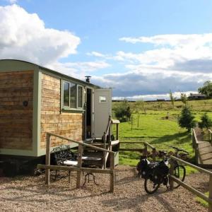 貝林翰的住宿－Lizzie off grid Shepherds Hut The Buteland Stop，一辆自行车停在房子前面的小房子