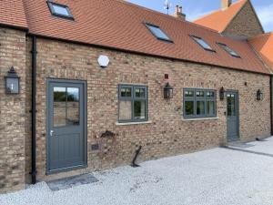 a brick building with a gray door and windows at Luxury Boutique Country Cottage with Hot Tub in York