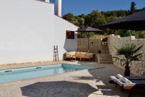 a swimming pool next to a building with an umbrella at Villa Bora - Blue Flat Green Flat in Slatine