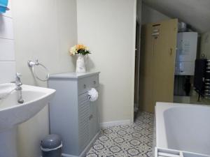 a bathroom with a sink and a vase of flowers on a cabinet at Ty Hen - Quirky Grade II Listed Cottage in Blaenau-Ffestiniog +21 photos