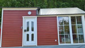czerwony budynek z białymi drzwiami i oknem w obiekcie Tiny House Strandwagen mit Terrasse w mieście Ahlbeck