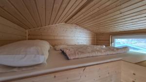 a bed in a wooden cabin with a window at Tiny House Strandwagen mit Terrasse in Ahlbeck