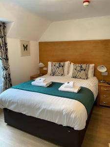 a bedroom with a large bed with two towels on it at The Claymore Guest House and Apartments in Pitlochry