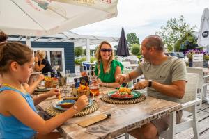 een groep mensen die aan een tafel eten bij Comfort Rooms by EuroParcs Bad Hulckesteijn in Nijkerk