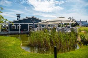a patio with tables and umbrellas in front of a building at Comfort Rooms by EuroParcs Bad Hulckesteijn in Nijkerk