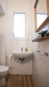 a white bathroom with a sink and a toilet at Casa Emilia [centro storico] in Imola