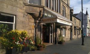 a hotel on a street with flowers in front of a building at The Gordon Arms Hotel in Huntly