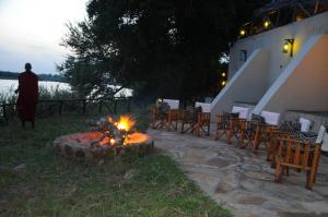 a fire pit with chairs and a man standing next to it at Selous Kulinda Camp in Selous Game Reserve