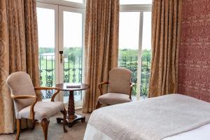 a bedroom with a bed and two chairs and a balcony at The Petersham in Richmond upon Thames