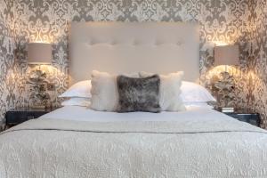a bedroom with a large white bed with two lamps at The Petersham in Richmond upon Thames