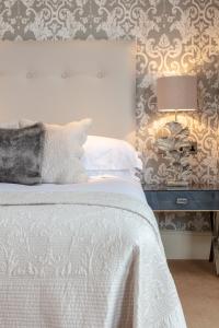 a bedroom with a white bed with a lamp and a wall at The Petersham in Richmond upon Thames