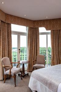 a bedroom with a bed and chairs and windows at The Petersham in Richmond upon Thames