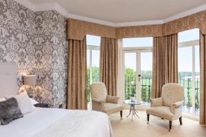 a bedroom with a bed and two chairs and windows at The Petersham in Richmond upon Thames
