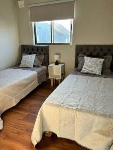 a bedroom with two beds and a window at Casa Nueva Sector Oriente Talca in Talca