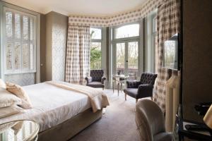 a bedroom with a bed and chairs and windows at The Petersham in Richmond upon Thames