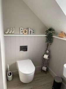 a white bathroom with a toilet and a shelf at The Old Coach House at BYRE HOUSE 