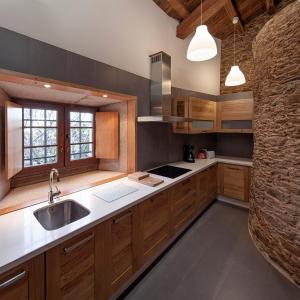 uma cozinha com armários de madeira e um lavatório em A Casacuberta em Marquiño