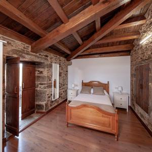 a bedroom with a wooden bed and a stone wall at A Casacuberta in Marquiño