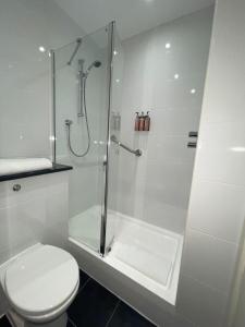 a white bathroom with a shower and a toilet at Heeton Concept Hotel - City Centre Liverpool in Liverpool