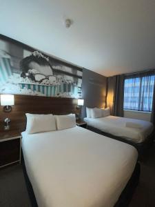 a hotel room with two beds and two windows at Heeton Concept Hotel - City Centre Liverpool in Liverpool