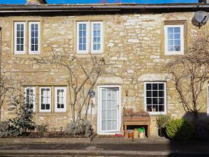 uma casa de pedra com janelas brancas e um banco na frente em Rose Cottage em Settle