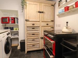 a kitchen with a stove and a wooden cabinet at Rose Cottage in Settle