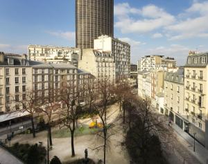 miasto z wysokimi budynkami i park z drzewami w obiekcie Hôtel du Parc Montparnasse w Paryżu