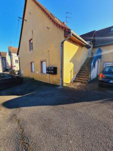 a yellow building with stairs and a car parked next to it at studio cosy in Vieux-Charmont