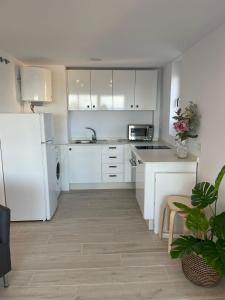 a kitchen with white cabinets and a white refrigerator at Apartamento Tres Banderas in Estepona