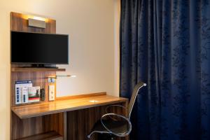 um quarto com uma secretária, uma televisão e uma cadeira em Holiday Inn Express Bremen Airport, an IHG Hotel em Bremen