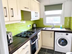 a kitchen with a stove top oven next to a washing machine at Rochester Townhouse with parking in Strood