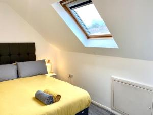 een slaapkamer met een geel bed en een dakraam bij Rochester Townhouse with parking in Strood